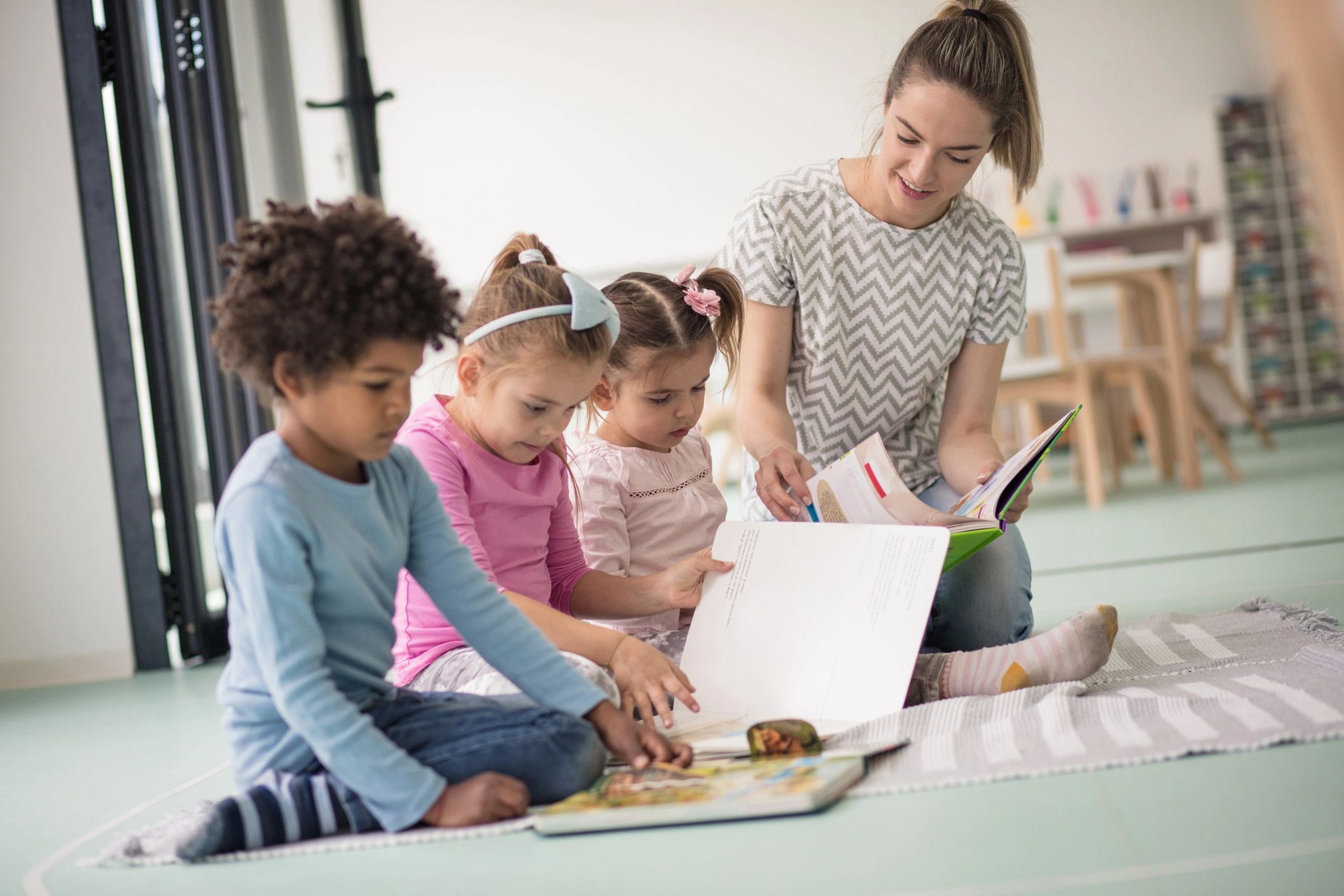 Preschool children learning together with a teacher nearby