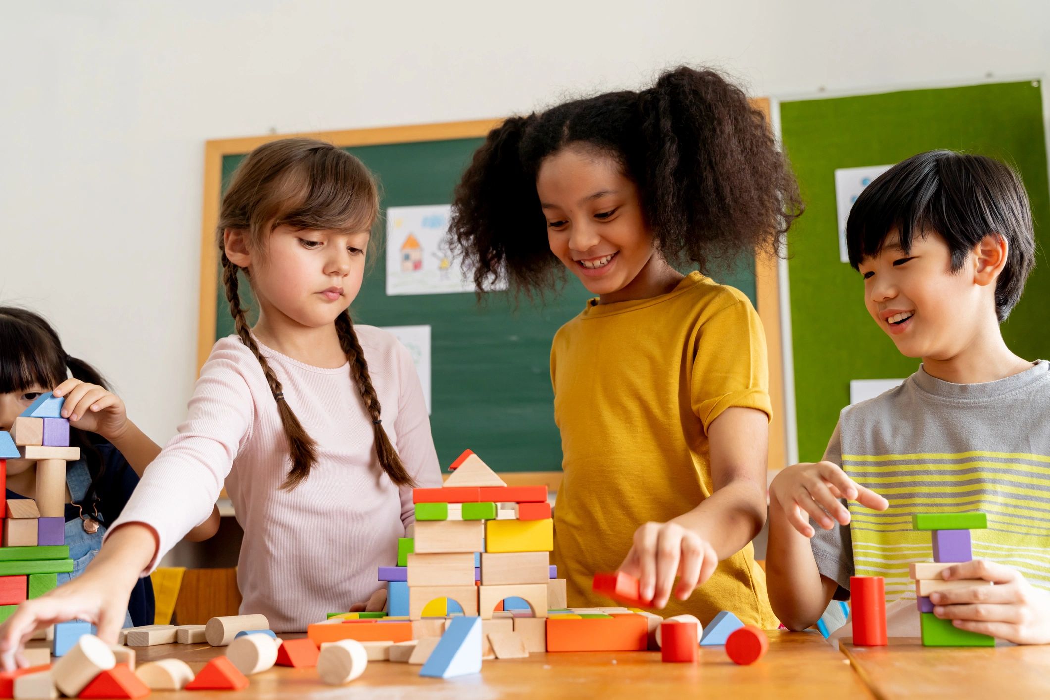 Children playing with wooden blocks together in a classroom