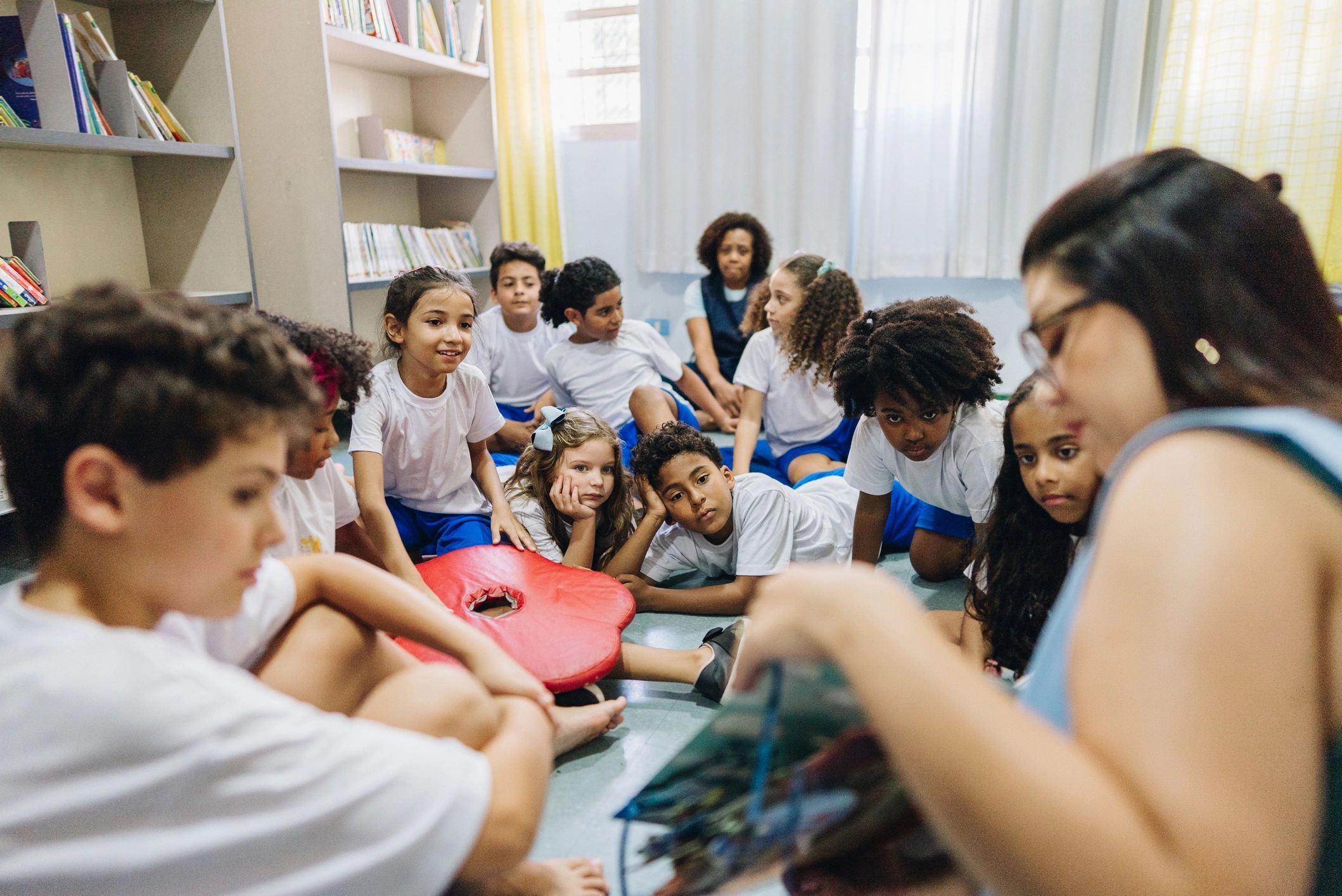 Children listening to a teacher reading a book at school