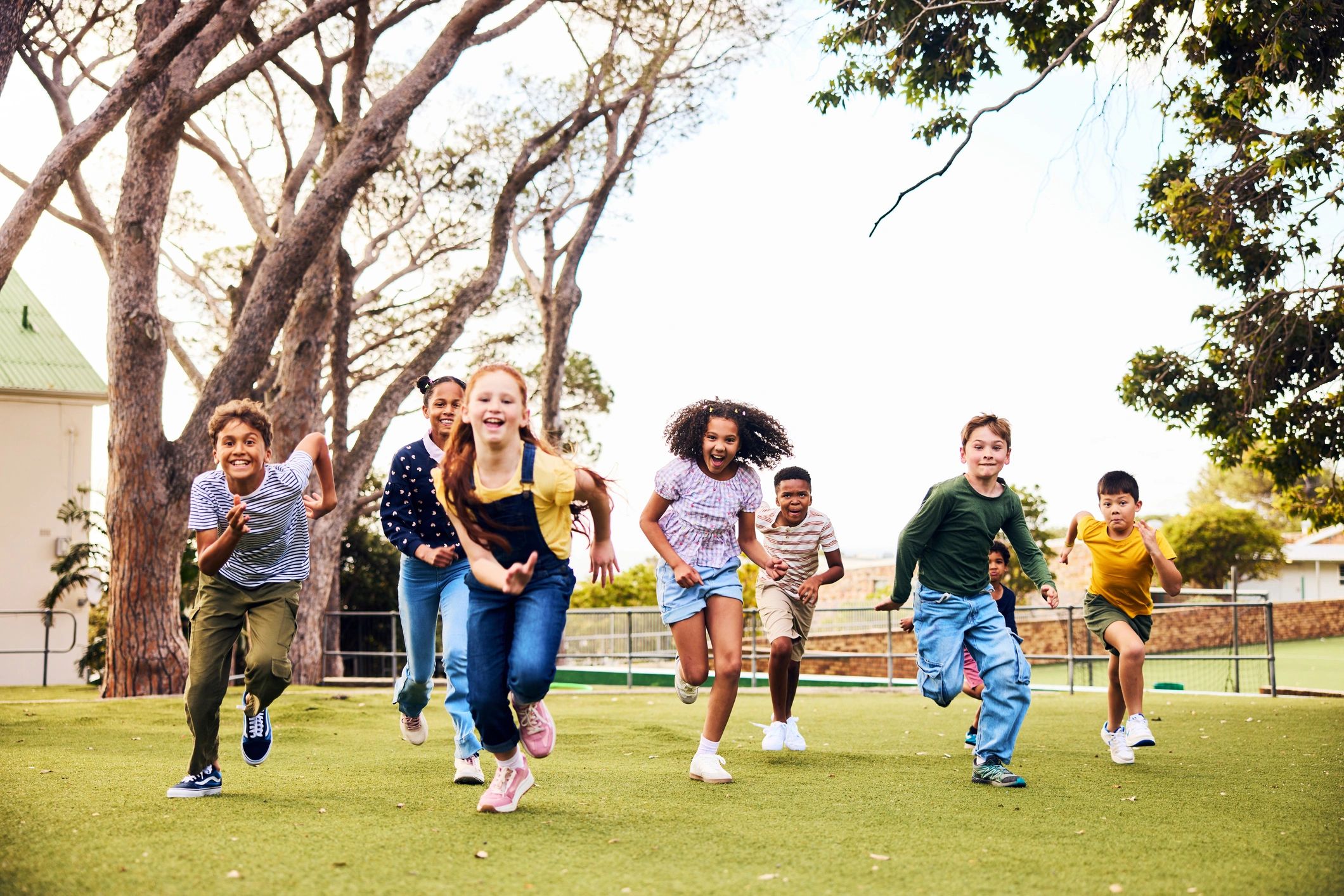 Group of children running together outside on a playground field